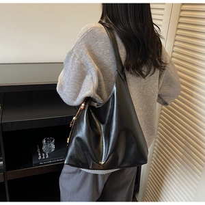 Detail of black large capacity hobo bag with contrast stitching and decorative beads