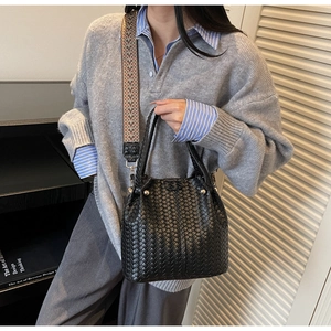 Close-up of woven black tote bag with geometric jacquard strap and gold stud detail
