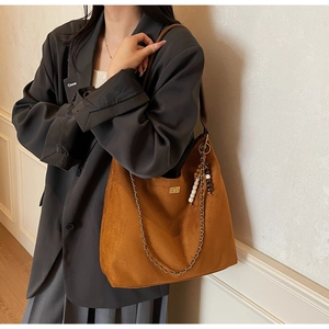 Détail du sac hobo en daim marron avec fermoir doré et pendentif en chaîne à perles