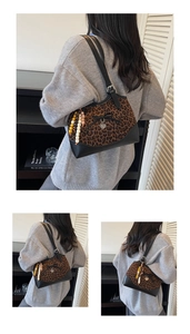 Detail of leopard print shoulder bag featuring a black bow and heart metal pendant