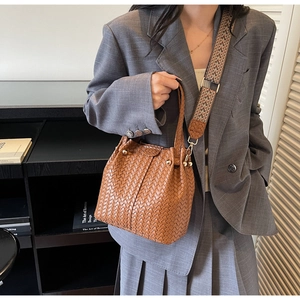 Close-up of brown woven bucket tote with geometric pattern adjustable fabric wide strap