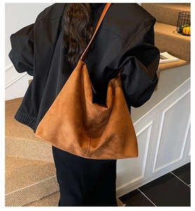 Detail view of large brown suede tote bag with seamless design and wide shoulder strap