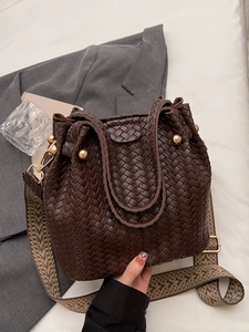 Vintage brown woven bucket bag with jacquard strap and gold hardware on neutral background