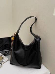 Large black hobo tote bag with white stitching and floral bead charm for daily commute