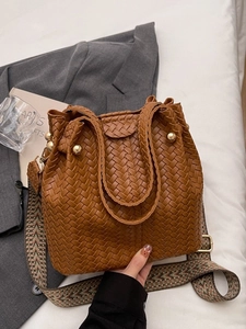 Brown woven bucket bag with gold metal orb detail and ethnic patterned shoulder strap