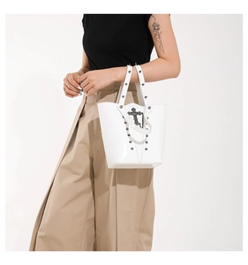 Close-up of white Y2K bucket bag with metallic rivets and vintage cross pendant detail