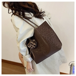 Large brown leather tote bag with leopard print panel and matching plush charm detail