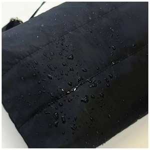 Détail du tissu matelassé noir imperméable avec gouttelettes d'eau sur la surface du sac