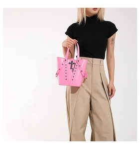 Detailed view of pink glossy punk bucket bag with cross metal ornament and silver rivets