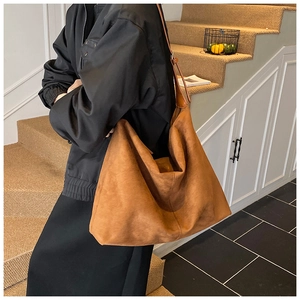 Detailed view of large caramel suede tote bag shown on shoulder for daily commute size guide