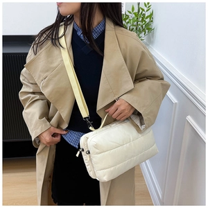 Sac fourre-tout matelassé crème avec bandoulière porté sur un trench-coat kaki