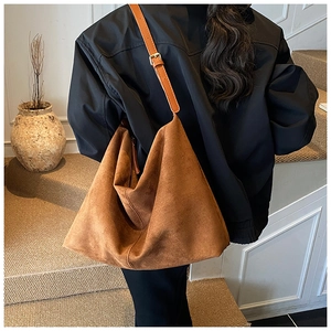Detailed back view of a large brown suede hobo bag with adjustable strap on a model