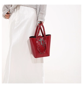 Detailed shot of red gothic bucket bag with embossed cross and silver metal rivets