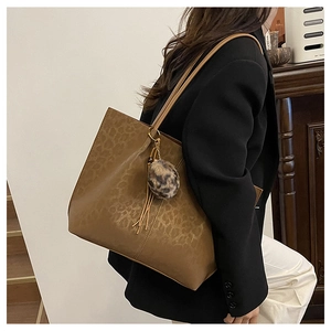 Close-up of leopard print tote bag with leather tassel and fur ball charm details