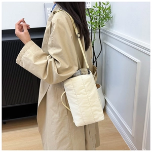 Détail du sac cabas matelassé beige avec coutures verticales et boucles métalliques