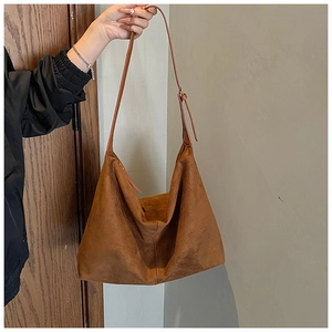 Detail of retro brown suede hobo tote bag featuring fine vertical stitching and adjustable strap