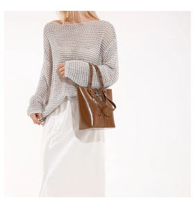 Detail of brown glossy bucket bag with silver studs and cross pendant decoration