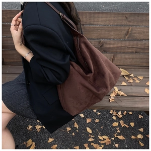 Close-up of large dark brown suede tote bag with leather strap in a warm autumn setting