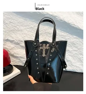 Detail of black glossy punk bucket bag with gothic metal cross and silver rivets