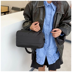 Détail d'un sac cabas matelassé noir avec coutures horizontales et bandoulière réglable