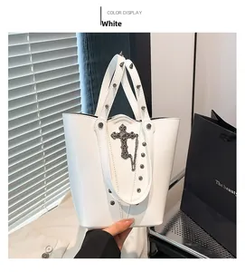 Detail of white bucket bag with punk metal crosses, decorative chains, and studded handles