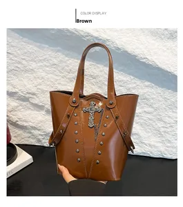 Detailed view of brown glossy leather bucket bag with silver studs and gothic cross pendant