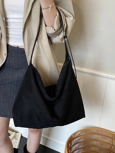 Minimalist black tote bag in premium matte finish shown on shoulder in office setting
