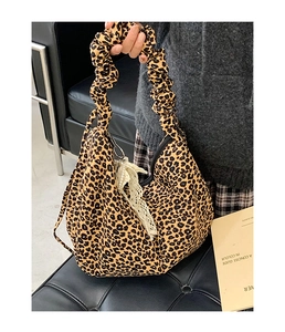 Detail of leopard print tote bag with ruched handle and white lace scarf accessory