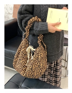 Close-up of canvas leopard print crossbody bag with pearl lace charm and ruffled handle