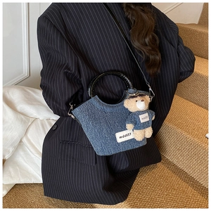 Sac seau en denim bleu foncé avec poignées rondes et breloque ours sur un mannequin
