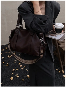 Detail of deep brown leather shoulder bag with a patterned woven strap on a model