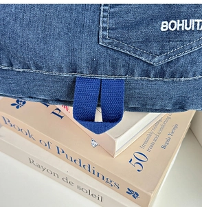 Detail of gradient denim backpack showing patch pocket and blue webbing loop with text