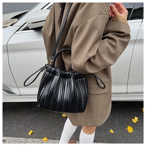Dettaglio di una borsa a secchiello plissettata nera con coulisse e tracolla donna