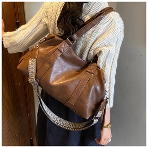 Detail showing deep brown leather tote bag with wide geometric woven shoulder strap
