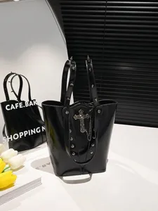 Gothic black bucket bag with metallic cross pendant and studded handle in Y2K style