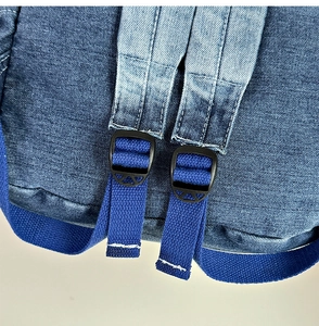Close-up of durable washed denim fabric and blue nylon strap on the backpack bottom