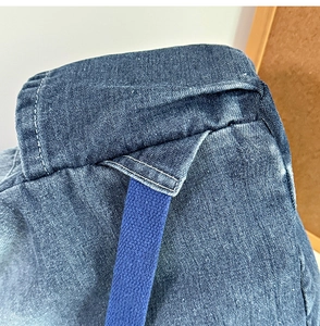 Macro view of blue gradient denim texture with woven drawstring and neat white stitching