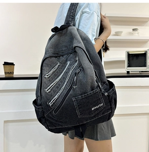 Detail of grey gradient denim backpack with distressed textures and multi-pocket design