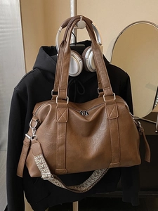 Brown large capacity leather tote bag with ethnic woven strap on casual display