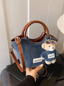 Sac seau en denim bleu avec anses en cuir marron et pendentif ours en peluche