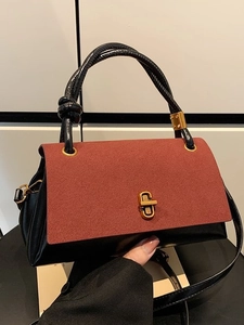 Borsa bicolore con patta rosso-marrone, corpo in pelle nera e chiusura geometrica dorata