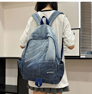 Detail shot of blue gradient denim backpack featuring multi-zipper pockets and wash texture