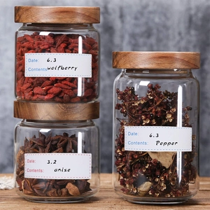 Airtight glass jars with wooden lids and food storage label stickers on a kitchen counter
