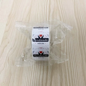 Macro detail of 'Handmade with love' round sticker rolls in clear plastic packaging