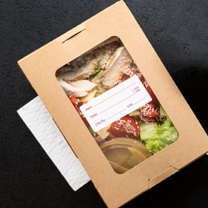 Close-up of food safety labels on kraft boxes for tracking dates and shelf life