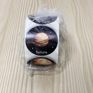 Detail shot of round space stickers with Saturn and Earth patterns on dark star background