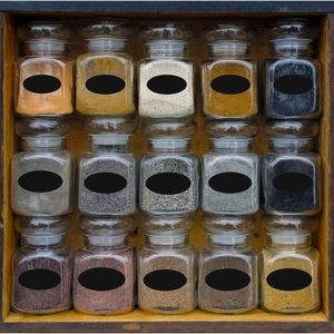 Waterproof chalkboard labels on glass spice jars organized in a natural wooden rack