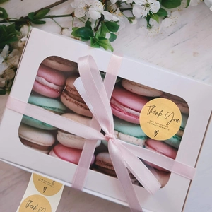 Nahaufnahme von Kraftpapier Thank You Aufkleber auf Macaron-Geschenkbox mit rosa Band