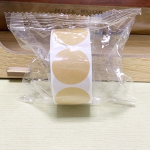 Detail of round kraft paper sticker rolls in transparent packaging on a wooden surface