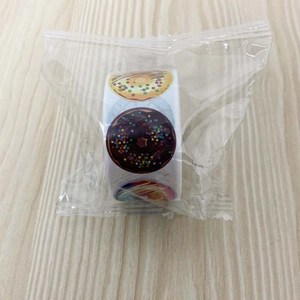 Roll of cartoon donut reward stickers in a polybag on light wood texture